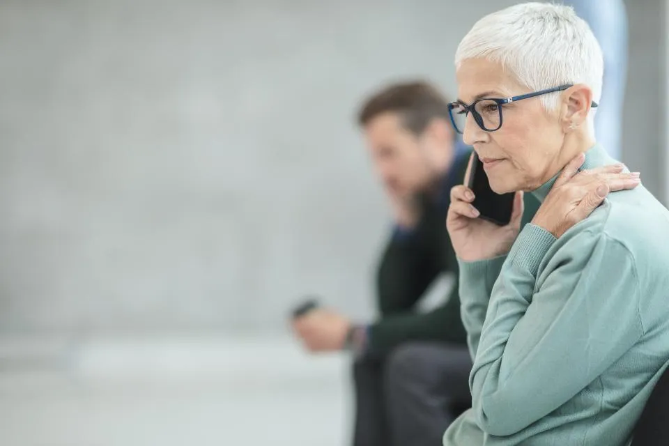 Povređena žena drži se za rame dok telefonom prijavljuje nezgodu
